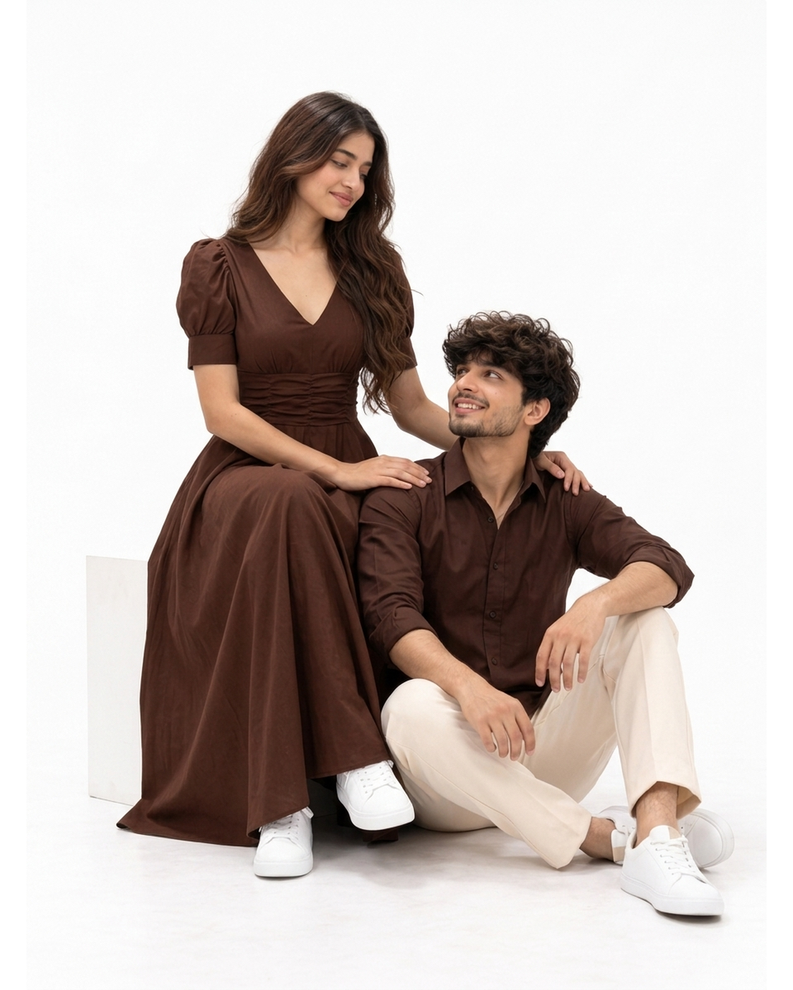 Cocoa Brown Dress & Shirt Couple Set - Seated Editorial Studio Pose on White Cube (Female Seated in Chocolate Maxi Dress, Male Relaxed on Floor Smiling Warmly, Pure White Background)